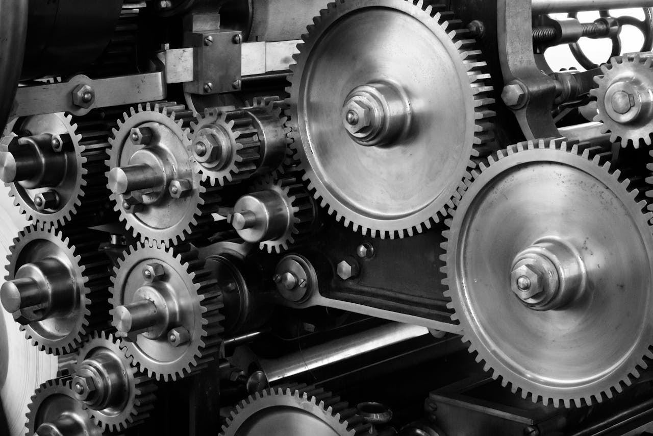 hero-img-01 Close-up view of a complex industrial gear mechanism in black and white.