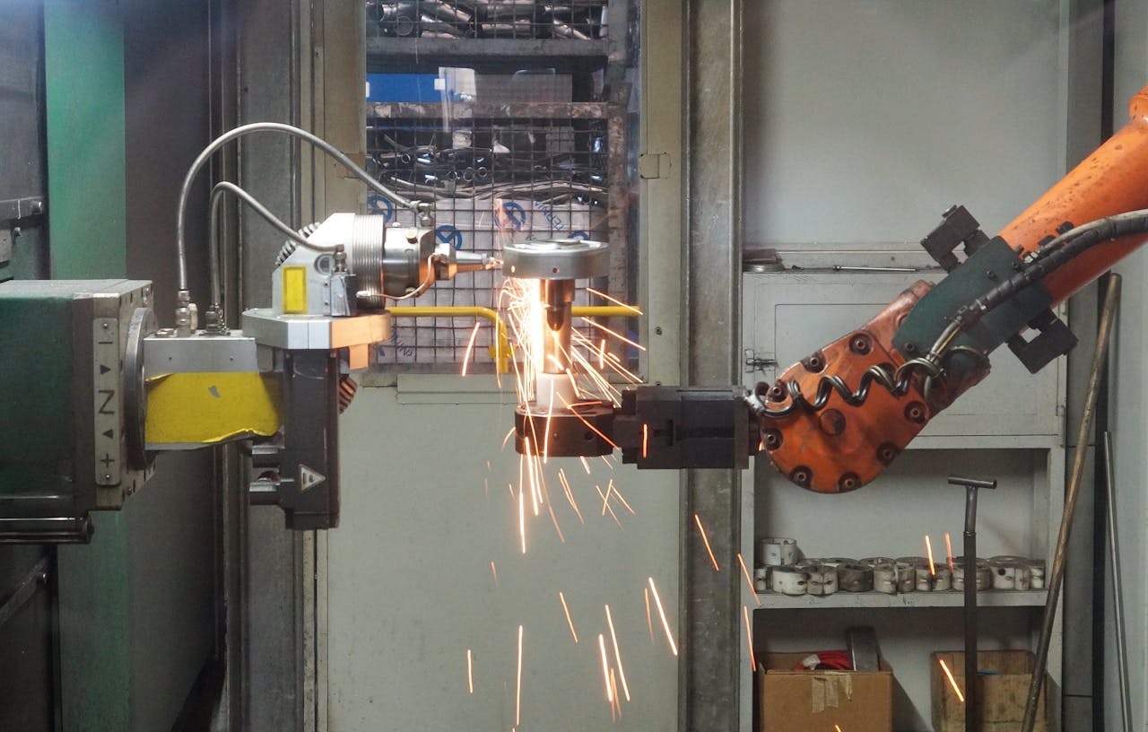 our-experience A robotic arm welding in an industrial setting, emitting bright sparks.