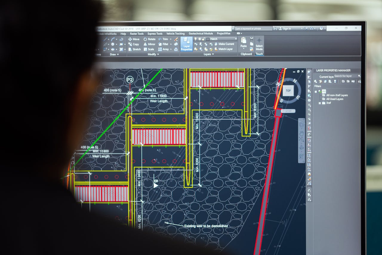 about-01 A civil engineer working on a weir design using CAD software on a computer screen in an office setting.
